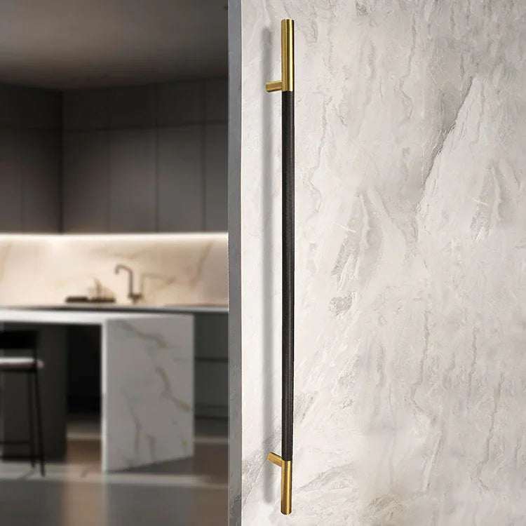 50-inch black and satin brass knurled ladder pull handle made of 304 stainless steel on a textured wall in modern kitchen setting